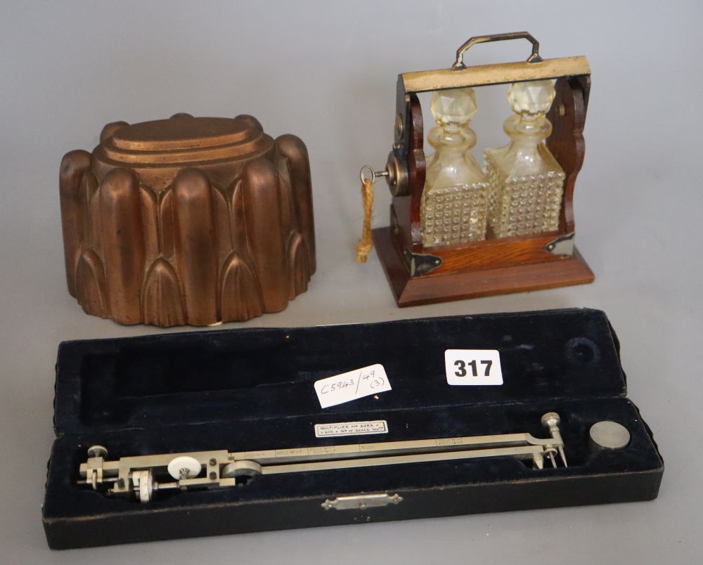 A miniature two bottle tantalus, height 17cm, a brass jelly mould and a cased multiplier